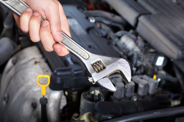 Alpha Romeo repair in Denver, CO. with AutoImports of Denver. Image of mechanic hand holding a big wrench over car engine for european car repair.