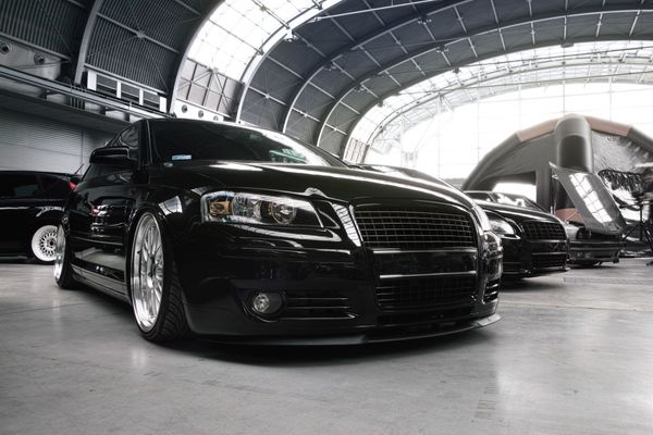 Audi repair in Denver, CO with AutoImports of Denver. Image of new black audi vehicles parked in a row in a bright open building with a dome shaped roof with windows.