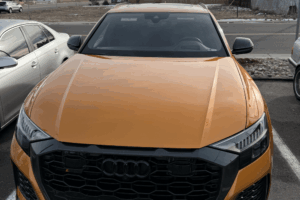 Audi Service in Denver, CO by AutoImports of Denver. Image of a bright orange Audi RS Q8 parked outdoors, showcasing the front grille and aggressive styling, ready for European vehicle service.